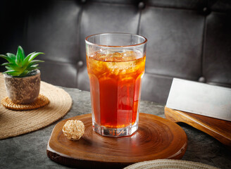 Refreshing iced tea beverage served on rustic wood coaster beside small succulent plant detail