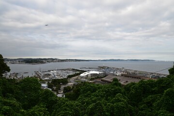 Panoramic view of Enoshima island and Sagami Bay in Kanagawa, Japan, featuring the yacht harbor and Shonan coastline under a cloudy sky.