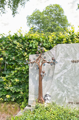 Baum aus Bronze mit Blättern vor einem Grabstein auf  dem Katholischen Friedhof in Kempten Allgäu © Blende8