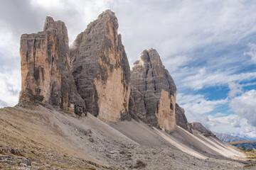 Low angel view of the North face of Tre Cime di Lavaredo peaks also called Drei Zinnen with white clouds in Dolomite Alps, near Cortina d'Ampezzo, Italy