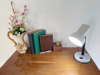 Desk with old book, light bulbs and artificial flower