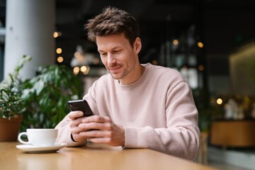 Man engaging with ai productivity app on smartphone in cozy cafe setting