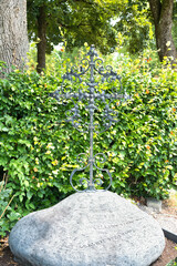 schön versiertes Eisenkreuz auf einem großen Stein auf dem Katholischen Friedhof in Kempten - Allgäu © Blende8