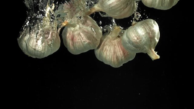 The heads of fresh garlic fall under the water. Filmed on a high-speed camera at 1000 fps. High quality FullHD footage