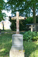 alter Grabstein mit einem Steinkreuz auf einem Waldfriedhof in Memmingen © Blende8