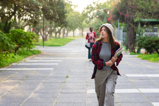 Diverse female students walking campus path carrying notebooks folders and guitar case, copy space