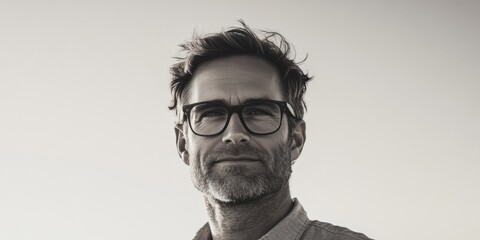A bearded older man wearing eyeglasses against a blurred background.