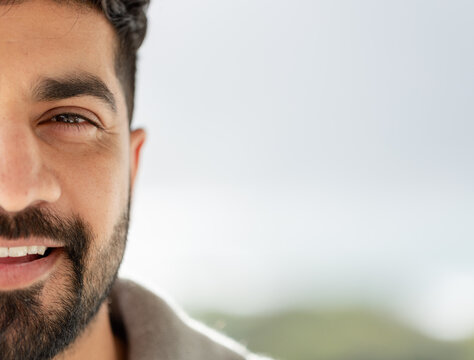 Indian man smiling while wearing collared shirt outdoors with blurred foliage backdrop, copy space