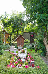 schönes Familiengrab mit einem großen Pflanzgefäß und einem hölzernen Grabstein auf dem Waldfriedhof in Memmingen © Blende8