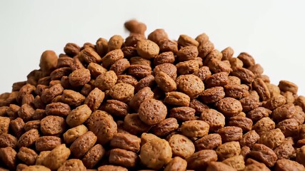 A raffes falling amidst nuts on a white surface create an interesting visual dynamic, symbolizing abundance and prosperity, perfect for use in banner or promotional materials highlighting a.