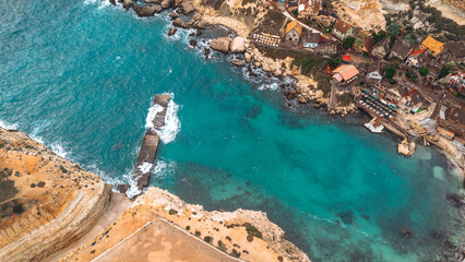 Aerial view of Popeye Village in Malta, with turquoise ocean and coastal scenery.