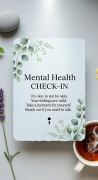 Card displaying encouraging message for emotional well-being rests on light surface near botanicals and warm beverage