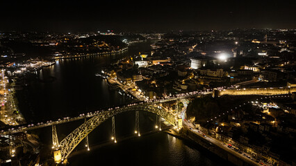 Obraz premium Porto at Night from Drone – Illuminated Riverside, Historic Cityscape, Douro River Lights and Old Town Architecture Captured in Stunning Aerial View. Portugal Aerial