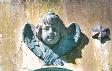 schöner Engelskopf, Putte als Dekoration an einem Grabstein auf einem Friedhof in Ulm © Blende8