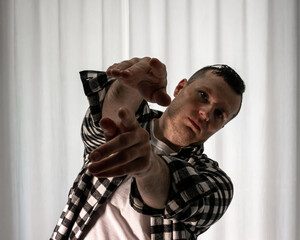 Young guy in a dancing pose on a white background. Modern dance in a plaid shirt. Sports plastic...