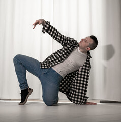 Young guy in a dancing pose on a white background. Modern dance in a plaid shirt. Sports plastic...