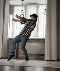 Young guy in a dancing pose on a white background. Modern dance in a plaid shirt. Sports plastic...