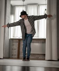 Young guy in a dancing pose on a white background. Modern dance in a plaid shirt. Sports plastic...