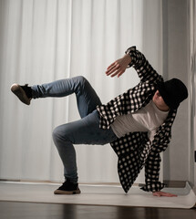 Young guy in a dancing pose on a white background. Modern dance in a plaid shirt. Sports plastic...