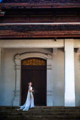 Naklejka premium Vertical pretty Thai woman in elegant Thai costume in old heritage architecture landmark