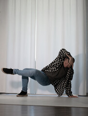 Young guy in a dancing pose on a white background. Modern dance in a plaid shirt. Sports plastic movements of arms and legs and body.