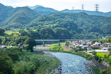 群馬県利根川とJR上越線鉄橋、夏の山々に囲まれた集落の風景 © OFFICE TK
