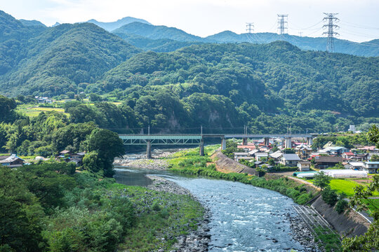 群馬県利根川とJR上越線鉄橋、夏の山々に囲まれた集落の風景