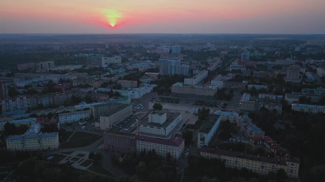 Aerial evening view of Orel city in Russia with river, Strelka, main buildings, churches and roads. Beautiful cityscape with lights reflecting on water at sunset, showing urban architecture, skyline.