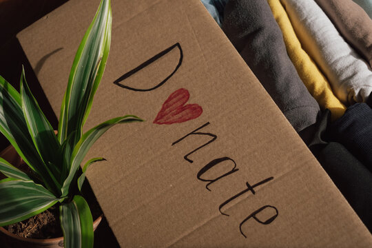 Many clothing items are organised in a donation box with a message promoting kindness and community support