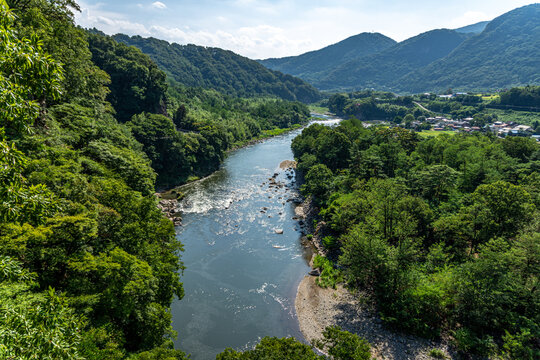 群馬県利根川の夏の渓谷、雄大な山並みと清流と集落