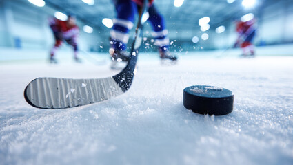 Close-up of a hockey stick striking a puck on snowy ice with sharp flying ice particles, dynamic motion blur, and players in colorful uniforms skating in the background