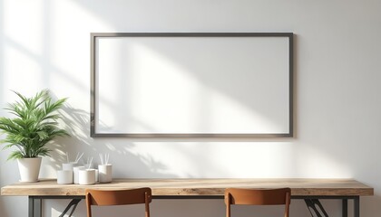 Modern minimalist office space interior with wooden desk and chairs. Large empty frame hangs on white wall. Potted plant and diffusers sit on desk creating clean, bright work environment.