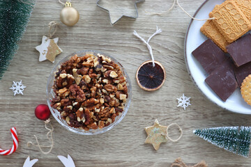 Various Christmas decorations, cookies, chocolate and nuts on wooden background. Flat lay.