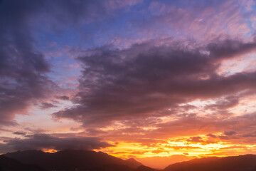 Bright sunset over the silhouette mountains at evening time.