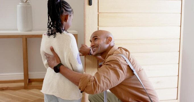 Father kneeling beside daughter tightening lock pressing keypad unlocking door in entryway