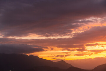 Bright sunset over the silhouette mountains at evening time.