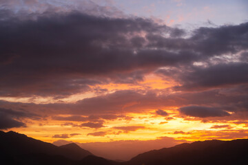 Bright sunset over the silhouette mountains at evening time.