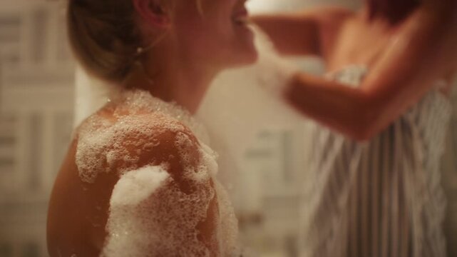 Women enjoy a traditional hammam bath experience, smiling and laughing as foam is applied. A fun and relaxing moment between friends at the spa.