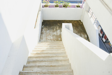 A concrete outdoor staircase with peeling paint in sunlight.