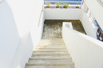 A concrete outdoor staircase with peeling paint in sunlight.
