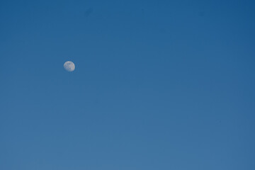 Bright blue sky with the moon visible during the day.