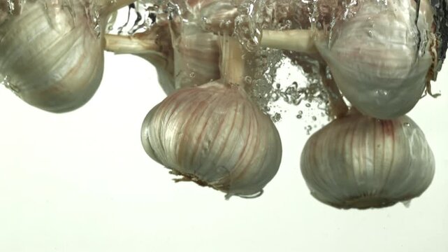 The heads of fresh garlic fall under the water. Filmed on a high-speed camera at 1000 fps. High quality FullHD footage