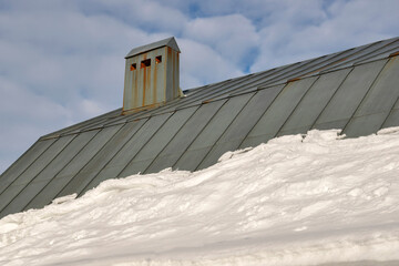 Roof of a house with a ventilation pipe and snow