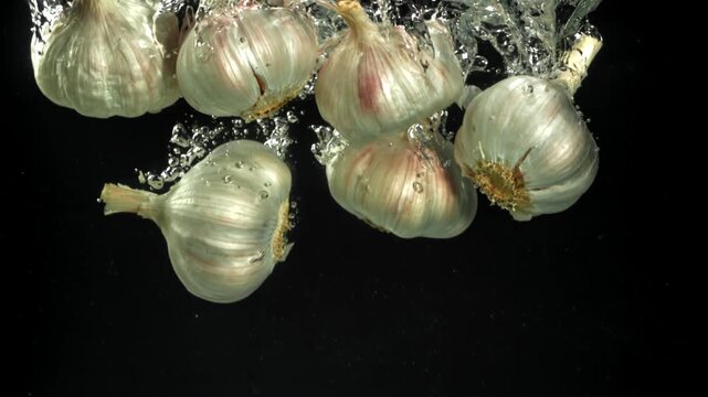 The heads of fresh garlic fall under the water. Filmed on a high-speed camera at 1000 fps. High quality FullHD footage