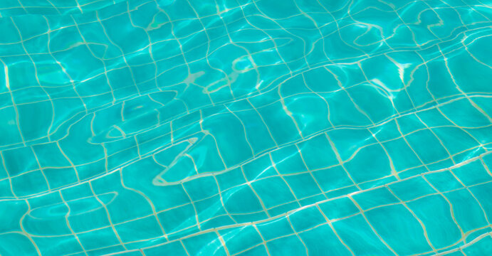 shimmering surface of a swimming pool with visible tile patterns and light distortions and turquoise water