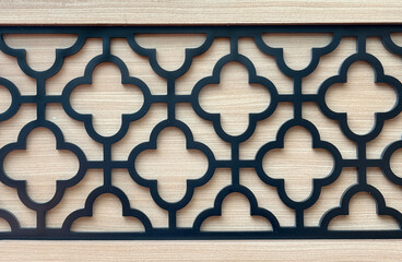 Close up of geometrical random flower and round clover ornamental shapes. 3D cutout laser cut decorative curved shapes in black paint and wood background. Seamless background texture.