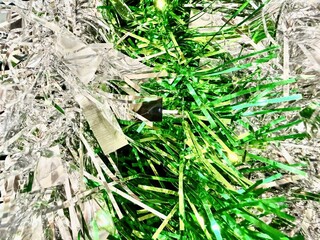 green silver shiny metallic tinsel strands tangled close-up macro texture with iridescent foil reflections and glitter highlights