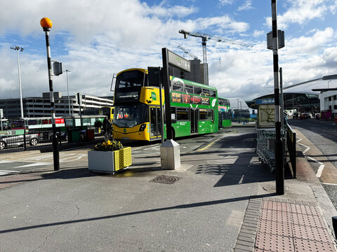 Dublin bus stop scene with a green double decker bus and people waiting at terminal