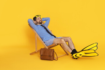 Businessman with diving mask and flippers in deck chair on orange background © New Africa
