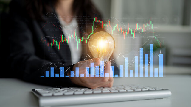 A business professional holds a glowing light bulb, symbolizing innovation amidst financial graphs and charts, representing modern investment opportunities and creative ideas. Scalp